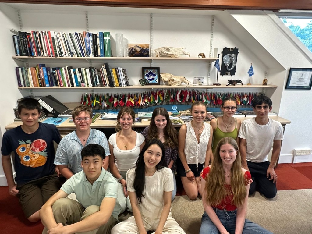 The OECM team gathered in a library, in front of shelves of books and a display of national flags