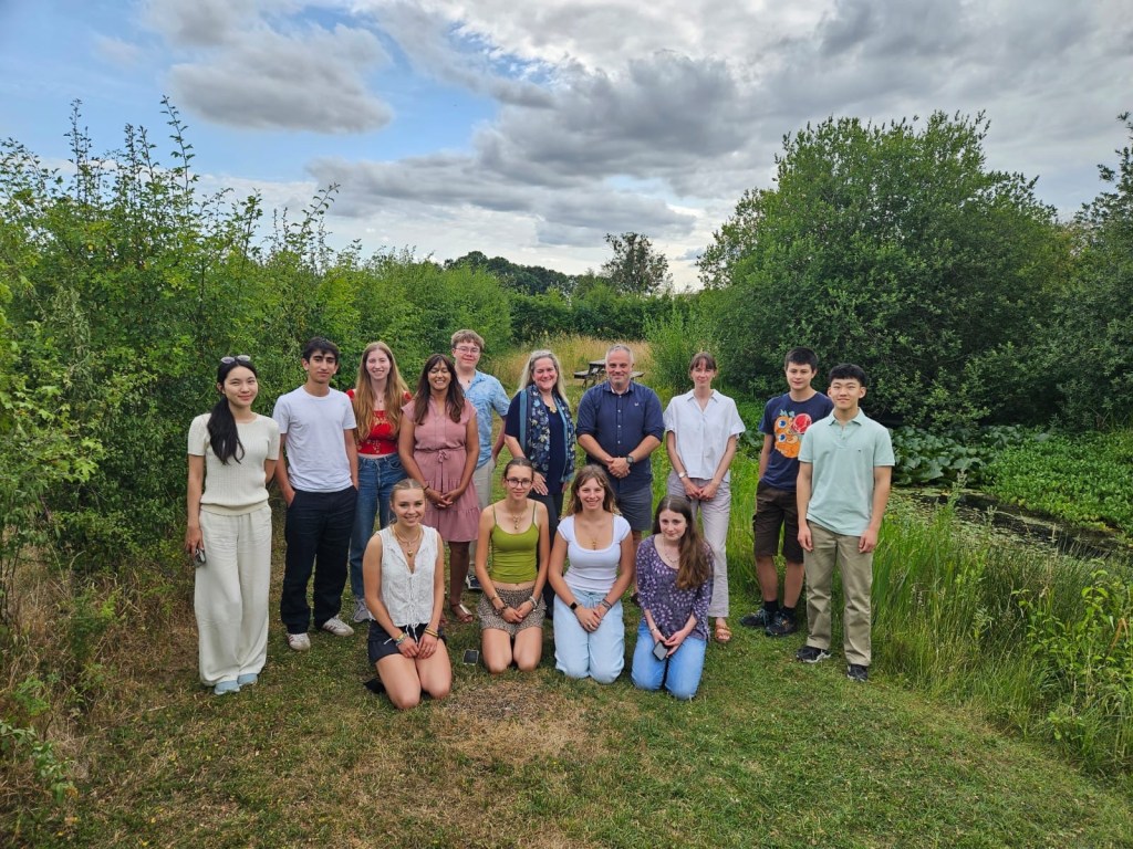 The OECM team standing together in a grassy area with trees and hedgerow behind them